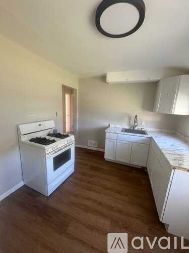 A kitchen with white appliances and wooden floors.