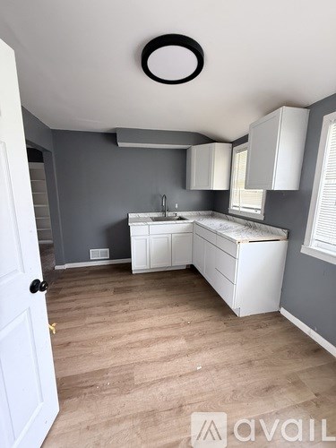A kitchen with a white sink and cabinets.