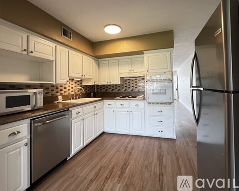 A kitchen with white cabinets and a wooden floor.