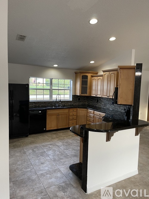 A kitchen with black appliances and wooden cabinets.