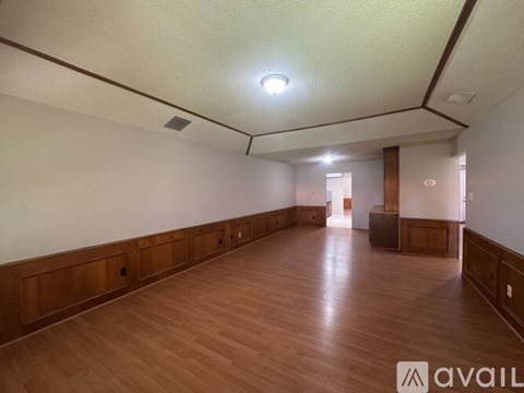A spacious room with wooden floors and white walls.
