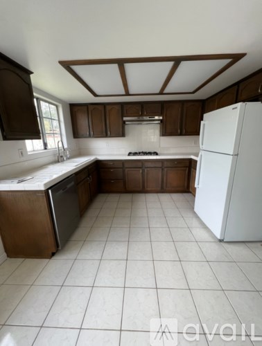 A kitchen with brown cabinets and a white refrigerator.