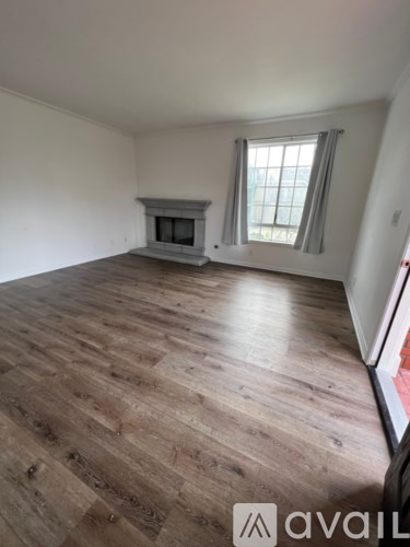 A room with wooden flooring and a fireplace.