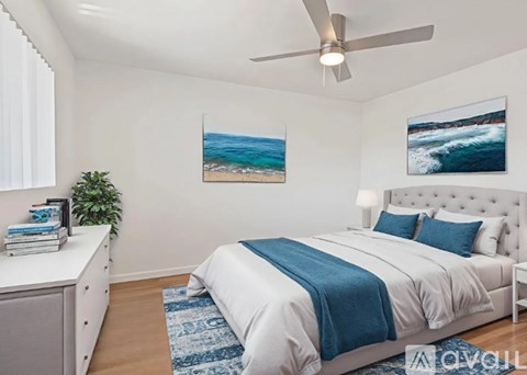 A bedroom with a white bed and a ceiling fan.