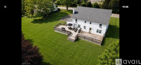 A white house with a black roof and a wooden deck.