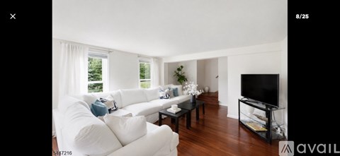 A living room with a white couch and a black television.