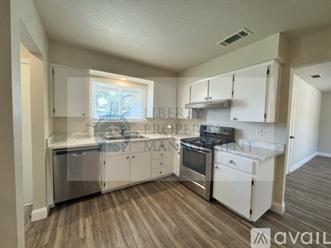 A kitchen with white cabinets and a wooden floor.