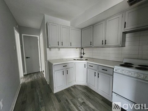 A kitchen with white cabinets and a stove top oven.