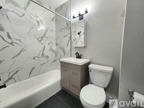 A bathroom with a marble patterned wall and a white toilet.