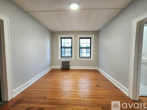 A room with wooden floors and two windows.