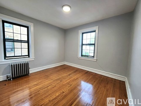 A room with wooden floors and two windows.