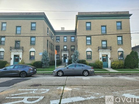 A street view of a building with cars parked in front.