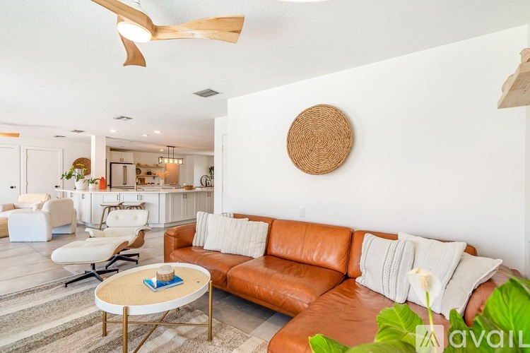 A living room with a brown leather couch and a round wooden decoration on the wall.