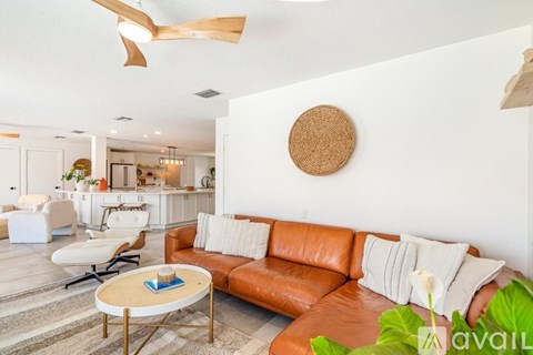 A living room with a brown leather couch and a round wooden decoration on the wall.