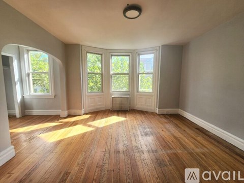 A room with wooden floors and a window overlooking a tree.