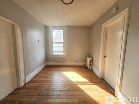 A room with wooden floors and a window letting in sunlight.