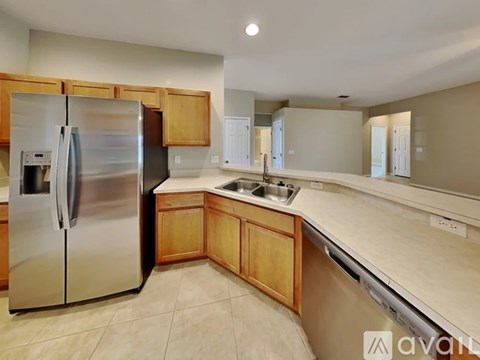 A kitchen with a stainless steel refrigerator and wooden cabinets.