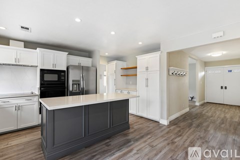 A kitchen with white cabinets and a black island.