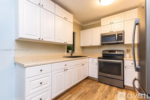 A kitchen with white cabinets and a wooden floor.