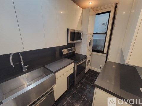 A modern kitchen with white cabinets and black countertops.