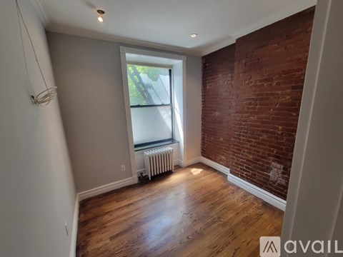 A room with a window and a radiator on the floor.