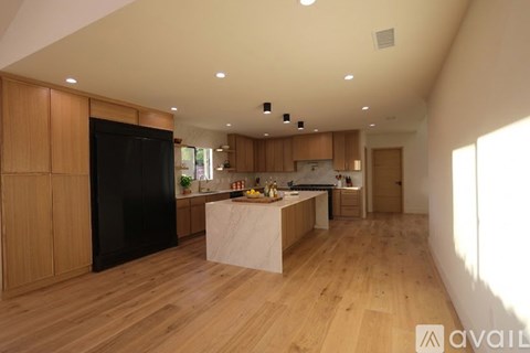 A kitchen with wooden cabinets and a black refrigerator.