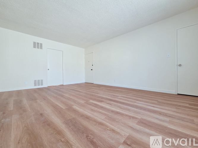 A room with wooden flooring and three white doors.