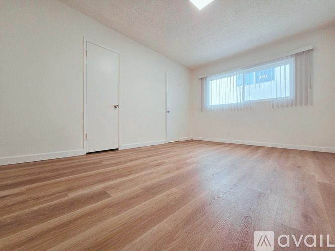 A room with wooden flooring and two doors.