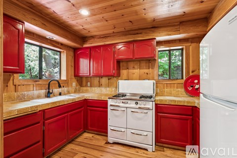 A kitchen with red cabinets and a white stove top oven.
