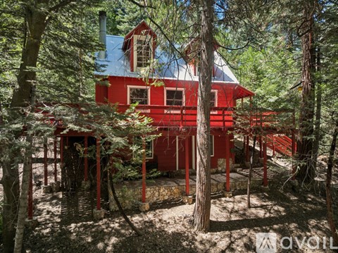 A red house with a white roof is surrounded by trees.