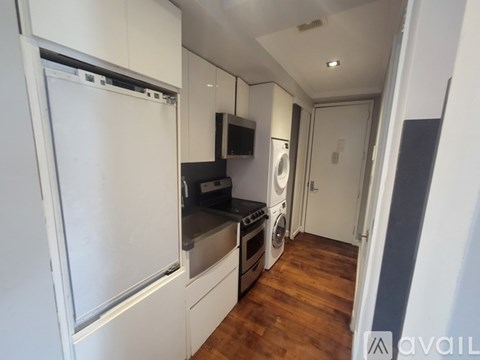 A kitchen with a white fridge, black stove, and white cabinets.