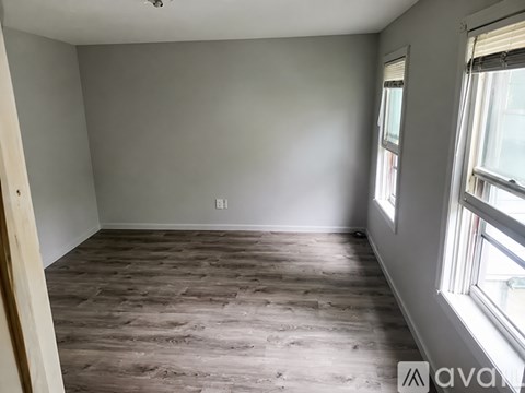 A room with wooden flooring and a window on the right side.