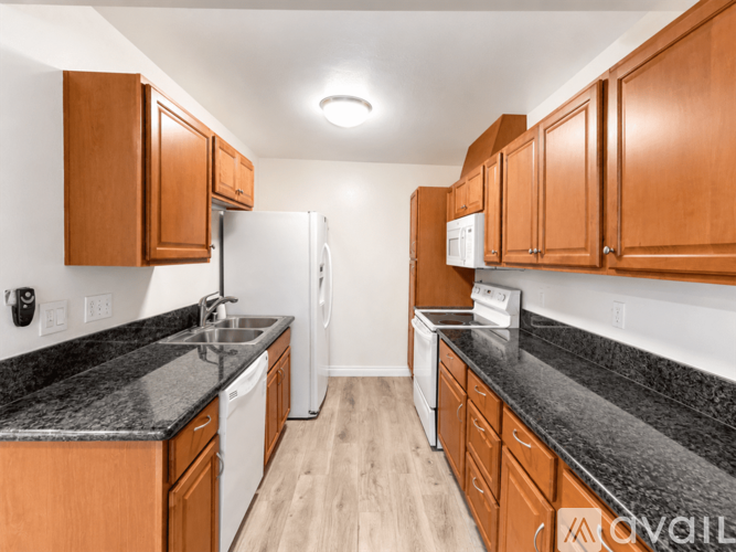 A kitchen with wooden cabinets and black countertops.