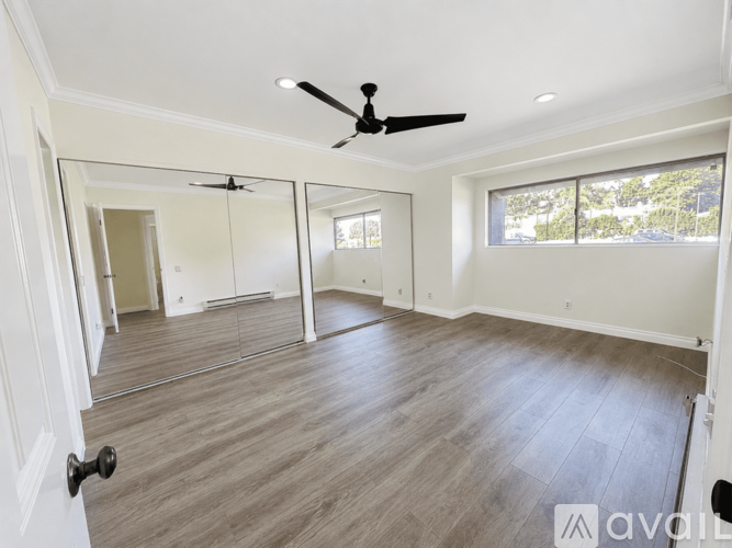 A spacious room with a ceiling fan and a large mirror.