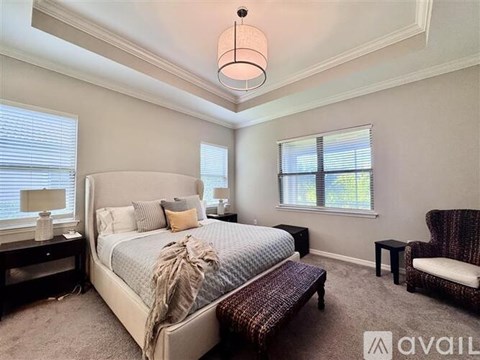 A bedroom with a large bed, a chair, and a window.