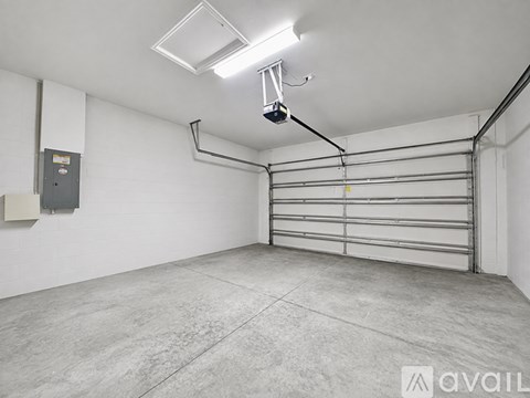 A spacious garage with a metal rolling shelf and a fluorescent light fixture.