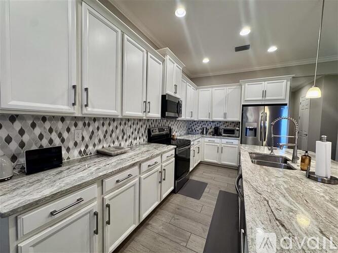 A kitchen with white cabinets and a marble countertop.