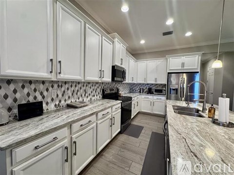 A kitchen with white cabinets and a marble countertop.