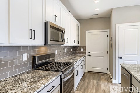 A kitchen with white cabinets and a granite countertop.