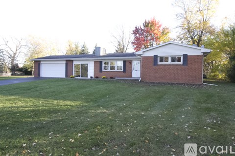 A house with a white garage door and a brick exterior is surrounded by a grassy lawn.