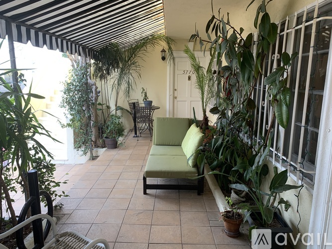 A patio with a green couch and plants.