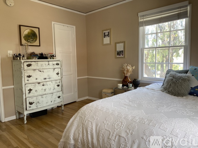 A bedroom with a white bed and a floral dresser.