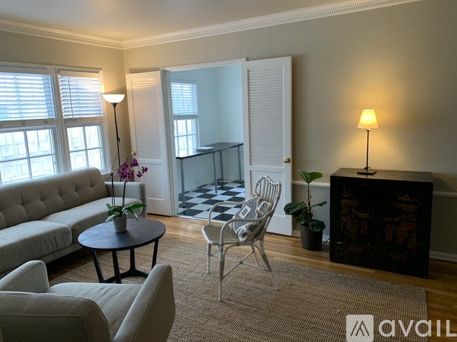 A living room with a sofa, chair, and a table with a vase of flowers on it.