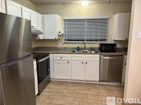 A kitchen with white cabinets and a stainless steel refrigerator.