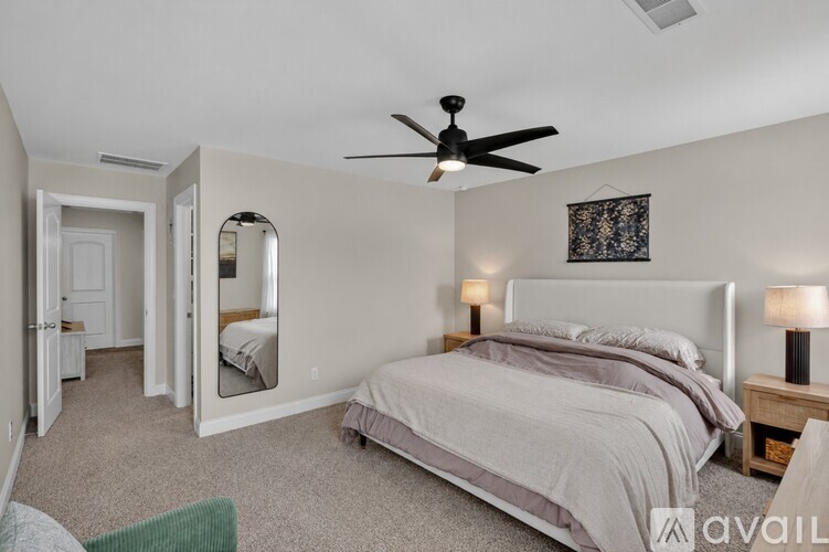A bedroom with a large bed and a ceiling fan.