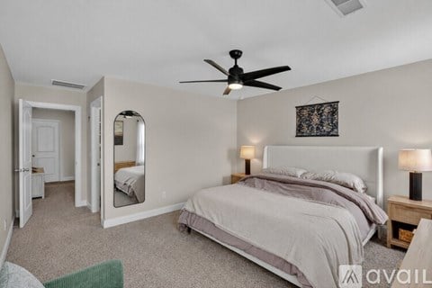 A bedroom with a large bed and a ceiling fan.