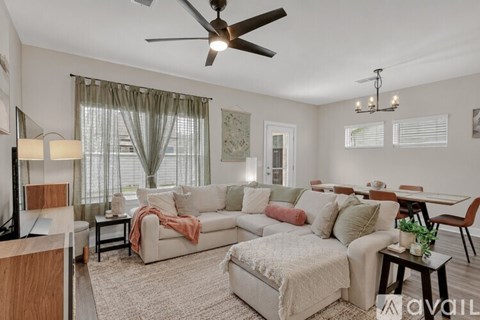 A living room with a white couch and a ceiling fan.