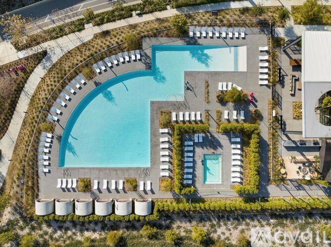 An aerial view of a pool surrounded by lounge chairs and greenery.
