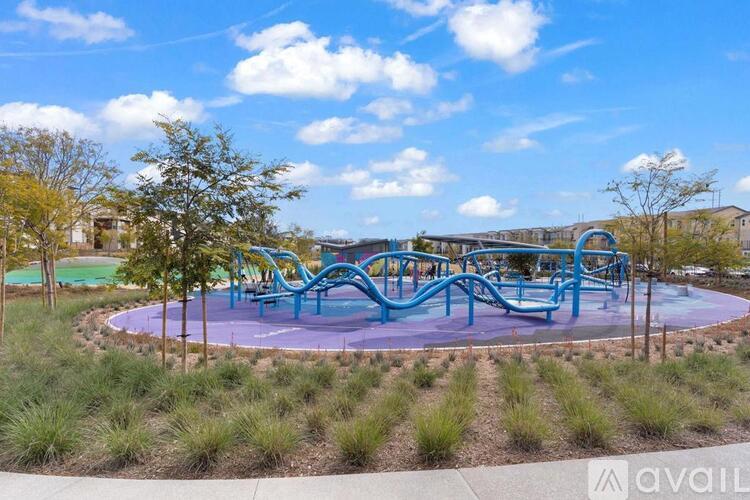 A playground with a blue and purple slide and a green tree.