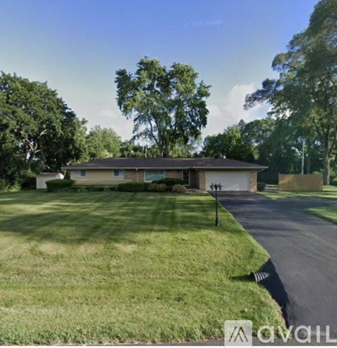 A house with a driveway and trees in the background.